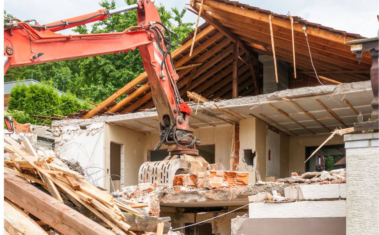 Excavadora derribando una casa como parte de una demolición con la obtención de un Certificado de Desratización pre-demolición.